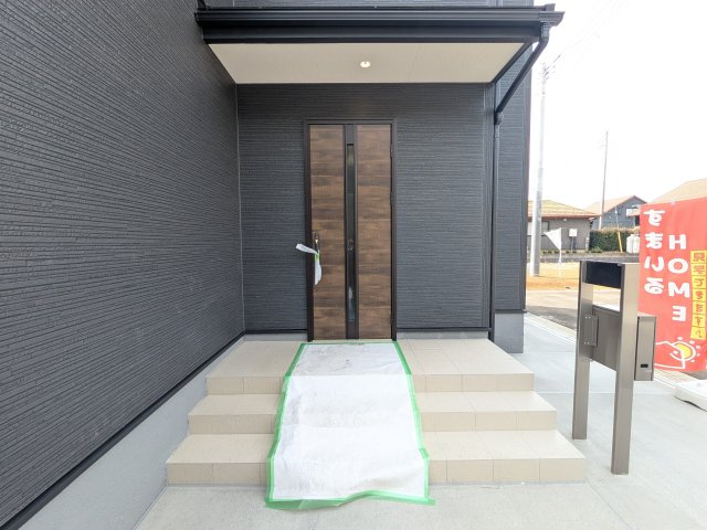 かすみがうら市下稲吉2期　新築戸建　6号棟の玄関|お洒落な玄関ドアと洗練された外壁デザイン。家の顔にふさわしい上質な佇まいで、ご家族やお客様を迎えます。