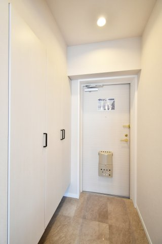 春日部ダイヤモンドマンションの玄関|白を基調とした内装に、大理石調のフロアタイルが映える美しい玄関空間。大型のシューズボックス付きで、家族全員の靴もスッキリ収納可能です。第一印象で心が躍る住まいの顔。