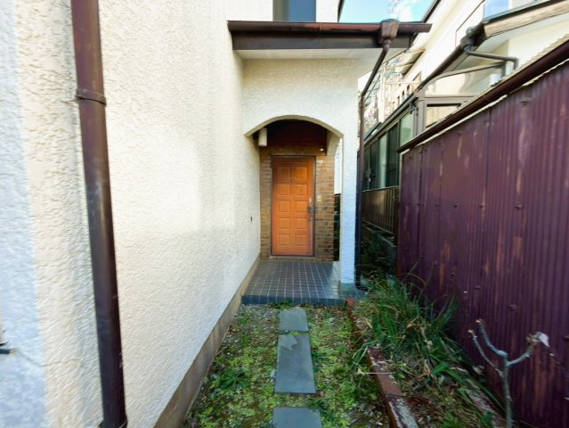 【湯河原町鍛冶屋】吹抜けがもたらす明るく開放的な室内の玄関|どこか懐かしく温かみのあるレトロな玄関。アーチ型のポーチが住まいの個性を引き立てます。