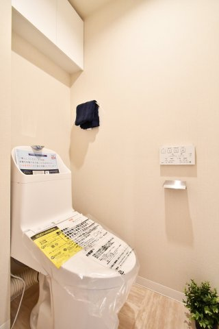 上尾ハウス2号棟のトイレ|新規交換済みの温水洗浄機能付トイレです。清潔感のある白を基調とし、上部には備品整理に便利な吊戸棚付き。快適なプライベート空間で、毎日の生活に安らぎをプラスします。