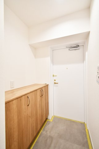 クラーク春日部壱番館の玄関|白を基調とした明るい玄関が、家族を優しく迎えます。フロアタイルも一新され、清潔感溢れる空間に。木の温もりを感じる下足入の上は、お気に入りの小物を飾るギャラリースペースとしても重宝します。