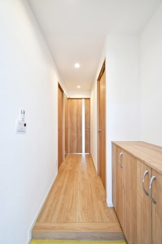 クラーク春日部壱番館の玄関|玄関から居室へと続く、質感豊かなフローリングが奥行きを演出。ダウンライトの柔らかな光が、リフォーム済みの美しい室内を照らします。扉を開けた瞬間に広がる開放的な住まいを、ぜひ現地でご体感ください。