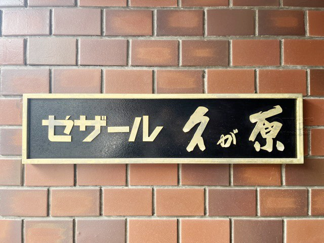 【現況写真】 | セザール久が原 | エントランスに掲げられた、マンション名を示す館銘板。さほど激しく主張はしませんが、しっかりと掲示されています。～即日のご見学可能～　お問合せはお気軽にどうぞ。