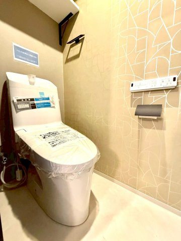 ノブヒル・ホドガヤのトイレ|洗練されたデザインクロスが印象的なトイレ空間。温水洗浄機能付きで快適性にも配慮され、細部まで上質さを感じさせる清潔感ある仕上がりです。