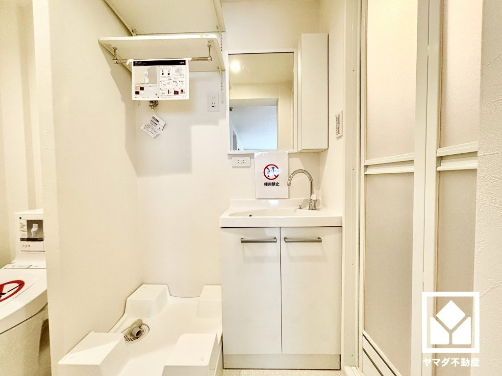 甲陽マンションの洗面所|収納付きでスッキリお使い頂けるLIXIL製の洗面化粧台を採用。室内洗濯機置き場の上部には、洗剤やタオルなどを置ける棚を備えており、日々の使い勝手にも配慮された仕様です。