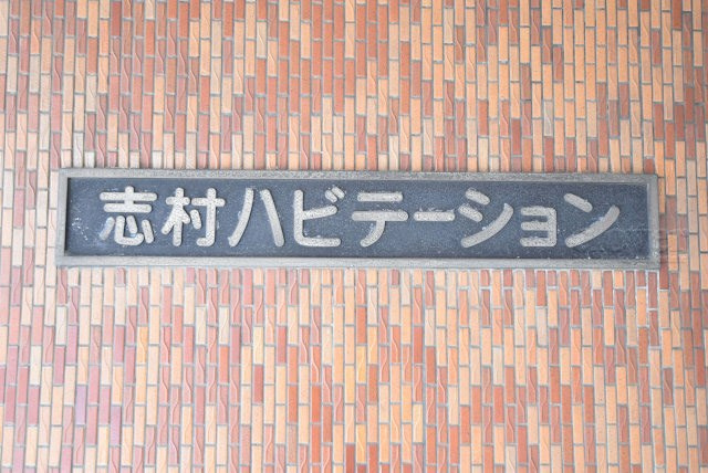 【現況写真】 | 志村ハビテーション | エントランスに掲げられた、マンション名を示す館銘板。さほど激しく主張はしませんが、しっかりと掲示されています。～即日のご見学可能～　お問合せはお気軽にどうぞ。