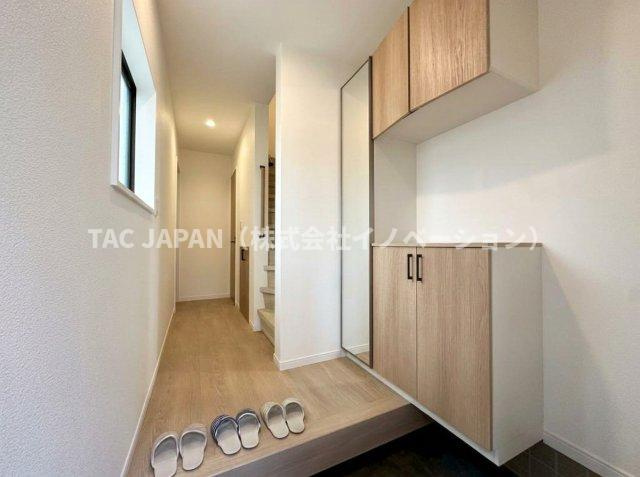 東上野の邸宅の玄関|日頃からスッキリ使いたい玄関スペースには姿鏡付きの天井まで届く大きなシューズクローゼットと廊下収納を完備。窓から日差しがそそぎ明るく清潔感ある雰囲気が創造されています。