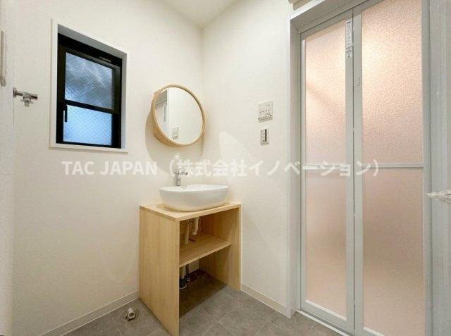 東上野の邸宅の洗面所|大型の洗濯機を置いても余裕が感じられる脱衣スペースにはお洒落な洗面ユニットを造作しました。コンパクトな設計ながら窮屈さはみじんも感じません。
