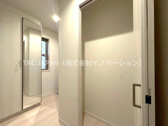 北区岩淵町の良邸の玄関|日頃からスッキリ使いたい玄関スペースには姿鏡付きの天井まで届く大きなシューズクローゼットと廊下収納を完備。玄関ドアの飾り窓から日差しがそそぎ明るく清潔感ある雰囲気が創造されています。