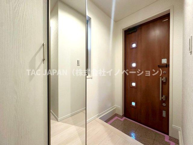 北区岩淵町の良邸の玄関|日頃からスッキリ使いたい玄関スペースには姿鏡付きの天井まで届く大きなシューズクローゼットと廊下収納を完備。玄関ドアの飾り窓から日差しがそそぎ明るく清潔感ある雰囲気が創造されています。