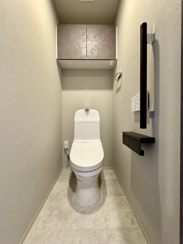 レ・ジェイド袋井駅前のトイレ|白を基調としたトイレには手すりや収納棚がついております。
