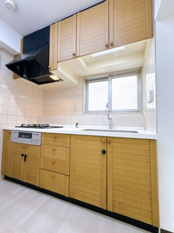 ピアコート戸塚参番館のキッチン|上下に収納を備えたシステムキッチン。木目調のデザインです。