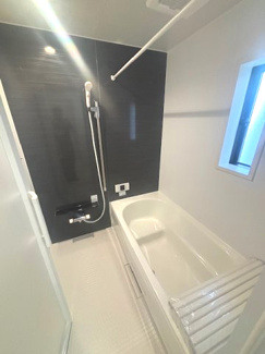 【浴室】 | 東広島市八本松飯田4丁目（全4区画）No2 | ブラックのアクセントパネルが落ち着いた雰囲気を演出するシステムバスです。ゆったりとした浴槽に加え、換気・採光に役立つ小窓を設置。天候を問わず洗濯物を乾かせる浴室乾燥機も完備しています。