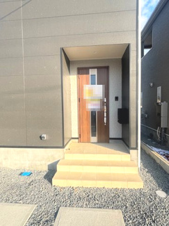 【玄関】 | 東広島市八本松飯田4丁目（全4区画）No2 | 木目調のドアがアクセントになった玄関ポーチ。屋根があるアルコーブ状の設計のため、雨の日の出入りもスムーズです。段差の少ない階段設計で、幅広い世代に配慮されています。