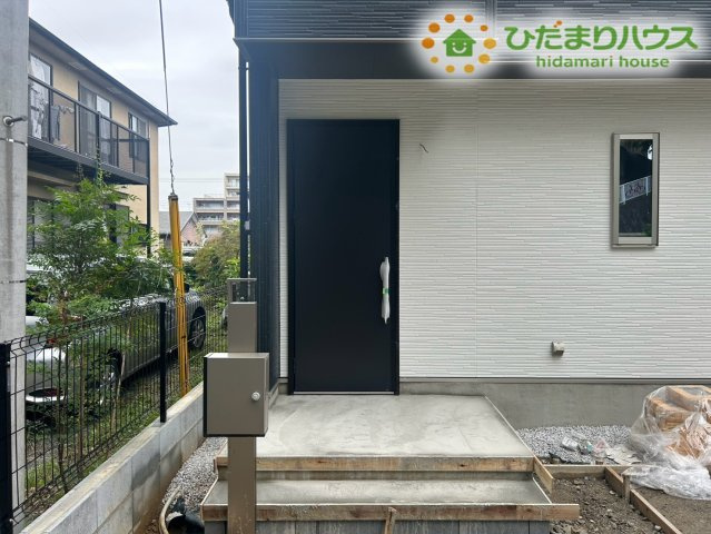 東松山市小松原町　新築一戸建て　01の玄関|重厚感のあるドアとスタイリッシュなポーチが印象的です！雨除け屋根が付いているため悪天候の際でも落ち着いて鍵の開閉が可能♪清潔感のある玄関前で毎日気持ちよく家族やお客様を迎えられますね！