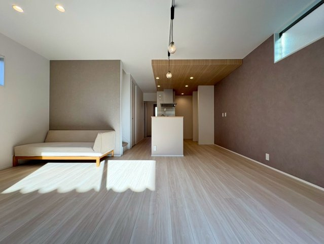 高知市福井町　新築一戸建ての居間・リビング|光が差し込む明るいLDK。落ち着いた色味の壁と木目天井が上質な空間を演出します