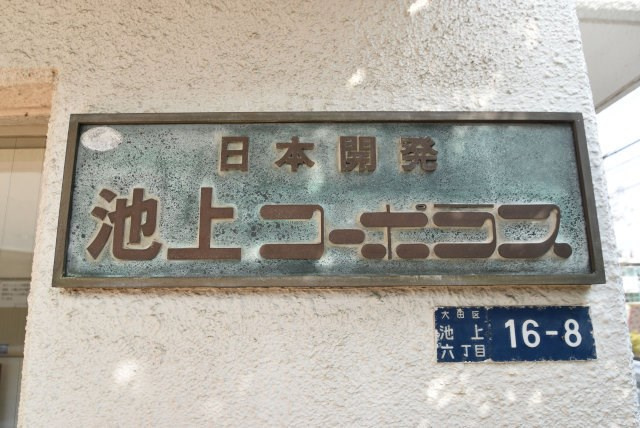 【現況写真】 | 池上コーポラス | エントランスに掲げられた、マンション名を示す館銘板。さほど激しく主張はしませんが、しっかりと掲示されています。～即日のご見学可能～　お問合せはお気軽にどうぞ。
