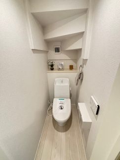 【トイレ】 | リナージュ八幡が丘2丁目（全1棟） | 階段下のスペースを有効活用したトイレです。圧迫感を感じさせないよう、明るい壁紙と小窓を配置。温水洗浄便座やタオル掛け、ペーパーホルダーなど、必要な機能がコンパクトにまとまっています。