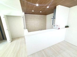 【居間・リビング】 | グランファーレ牛野谷町3丁目　全1棟 | キッチン上部は木目調の折り下げ天井とダウンライトを採用し、空間に奥行きと上質さをプラス。背面にはカップボードを置くスペースも十分にあり、背面のアクセントクロスが洗練された印象を与えます。