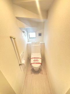 【トイレ】 | グランファーレ牛野谷町3丁目　全1棟 | 階段下のスペースを有効活用した1階トイレ。手洗い付きのローシルエット型で、空間を広く感じさせます。小窓からの採光により明るく、立ち座りをサポートする手すりも設置された安心設計です。