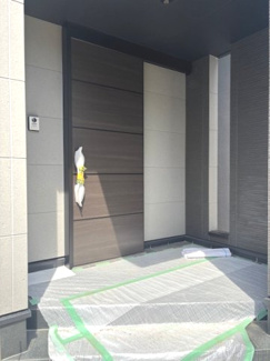 【玄関】 | 中区江波西1丁目（舟入南電停）全1区画【外構込み】 | 落ち着いた木目調の玄関ドアが、住まいの顔として上質な印象を与えます。庇（ひさし）があるため、雨の日でも濡れずに鍵を開け閉めできるのが魅力。モニター付きインターホン完備で防犯面にも配慮しています。