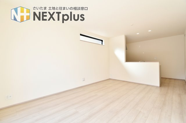 伊奈町栄四丁目76番　全1棟の居間・リビング|プライバシーに配慮した高所の横長スリット窓が、採光とデザイン性を両立。外からの視線を遮りつつ、室内に明るさを届けます。スッキリとした壁面は大型テレビの配置にも適しており、快適なTVライフを叶えます。