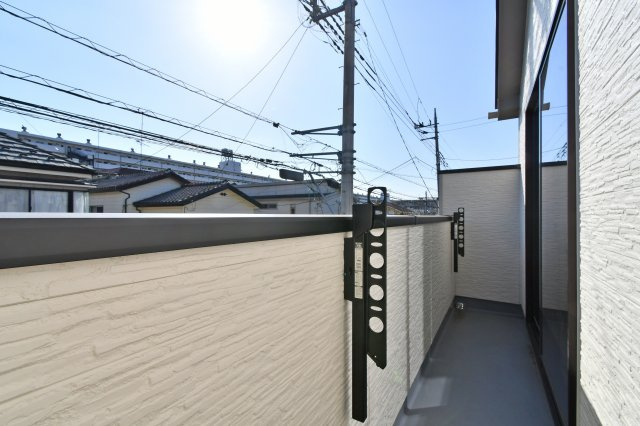 伊奈町栄四丁目76番　全1棟のバルコニー|明るい陽光が差し込むバルコニー。横幅もゆとりがあり、家族全員の洗濯物を一度に干せる十分なスペースを確保しています。手すり壁がプライバシーを守りつつ、心地よい風と光を室内に届ける設計です。