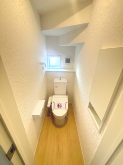 【トイレ】 | 東広島市八本松飯田4丁目（全4区画）No１ | 階段下のスペースを有効活用したトイレ。小窓による採光と換気が確保されています。温水洗浄便座を標準装備し、壁面にはトイレットペーパーのストック等に便利な扉付きの収納棚も設置されています。