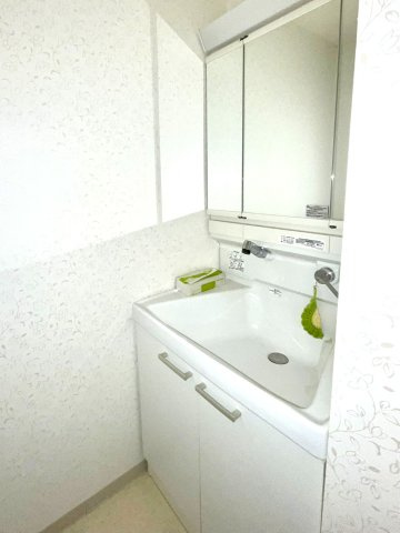 レジデンス大手前Ｂ棟の洗面所|洗面化粧台は３面鏡の裏側部分にも日用品をすっきり収納できます。コンパクトな脱衣室です。