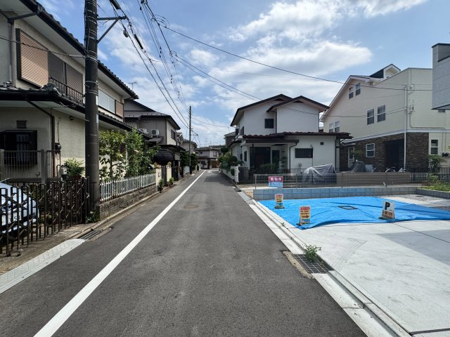 入間市東藤沢1丁目新築戸建の前面道路含む現地写真|前面道路は視界が開けており、車同士のすれ違いや後退駐車もスムーズに行える道幅が確保されています。障害物が少なく見通しが良いため、小さなお子様の歩行や自転車の通行時も安心感がある道路環境です。