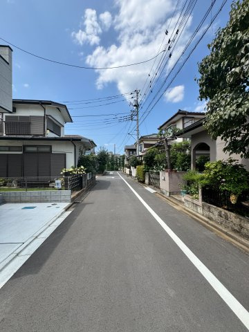 入間市東藤沢1丁目新築戸建の前面道路含む現地写真|整然と整備された綺麗な前面道路に面しており、すっきりとした街並みが広がっています。高低差が少なく平坦なアプローチのため、ベビーカーの押し引きや徒歩での移動も快適に行えるストレスフリーな立地です。