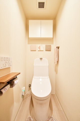 コスモ浦和辻のトイレ|白を基調とした清潔感あふれるトイレは、温水洗浄便座付きで快適な使い心地。上部には扉付きの吊戸棚を備えており、消耗品や掃除用品を生活感を出さずにスッキリと収納できる機能的な空間です。