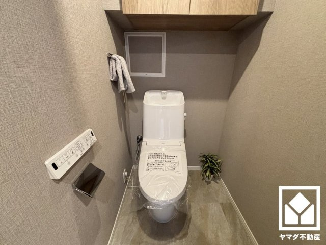 アンビエント西宮仁川アールブリーズのトイレ|明るく清潔感溢れるトイレです。温水洗浄便座付きで、季節を問わずいつでも温かい便座をお使いいただけます。トイレットペーパーのストックや消耗品置き場などとしてお使いいただける吊戸棚がございます。