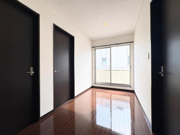 望みが丘　戸建ての内装|ダークブラウンのフローリングと扉が特徴的なフリースペースです。シンプルな色合いで清潔感があります。バルコニーとつながる空間です。