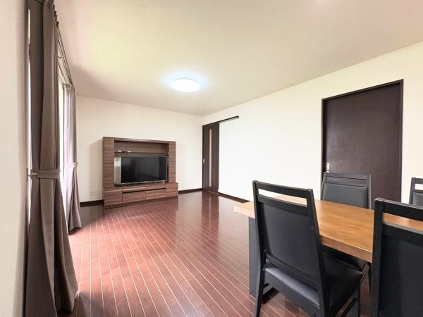 望みが丘　戸建ての居間・リビング|落ち着いた色合いのフローリングが印象的です。窓からの光が明るさを引き立てています。スペースにゆとりが感じられるリビングです。ドアや家具の配色が調和しています。