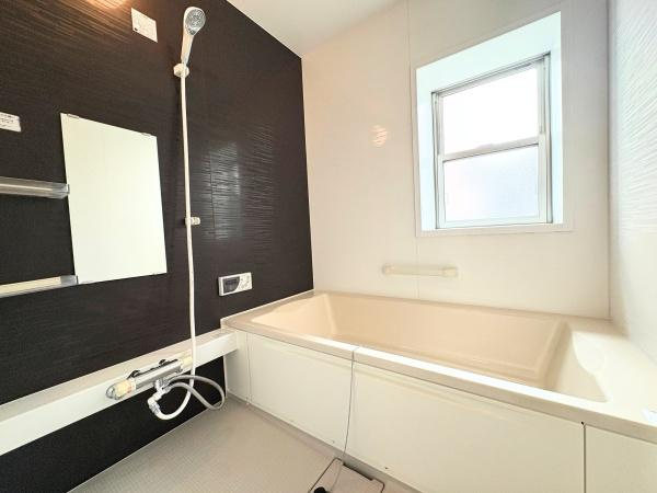 望みが丘　戸建ての浴室|広々とした浴槽が設置されており落ち着いた配色の壁面が特徴です。大きな窓から自然光が取り込めるため室内が明るい印象です。清潔感のある空間で毎日のリフレッシュをサポートします。