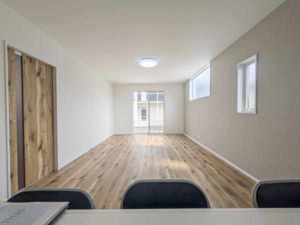 P-TELAS横田2丁目の居間・リビング|リビングは広々とした空間が広がっています。窓からの採光が十分に確保されています。やさしい色合いの床材が落ち着いた雰囲気を演出しています。壁のアクセントカラーが空間にメリハリを与えています。