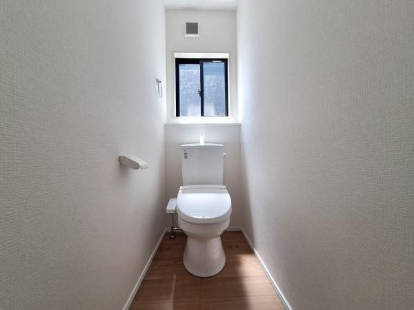 久原北1期2号棟のトイレ|明るい窓付きのトイレ空間です。白を基調とした内装で清潔感があります。床は木目調で落ち着いた雰囲気です。換気がしやすく快適にご利用いただけます。無駄のないシンプルな設計です。