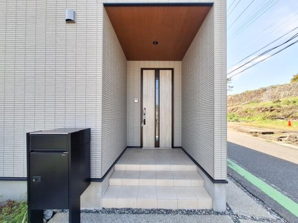 CASA BIANCA No.1の玄関|玄関はシンプルでスタイリッシュなデザインです。段差があるため外からの視線を遮りやすい構造です。広めのポーチスペースがあり機能的です。郵便受けも玄関付近に配置されています。