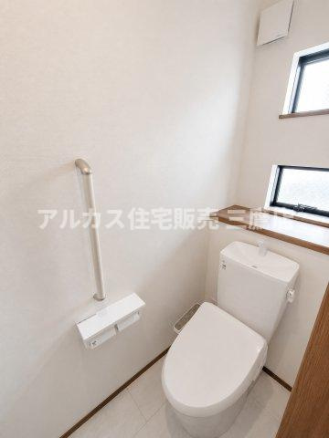 京王線 仙川駅 徒歩7分 新築戸建 調布市仙川町３丁目のトイレ|手すりやペーパーホルダーを備えたバリアフリー配慮のトイレ。小窓やカウンタースペースもあり、明るく快適な空間です。
