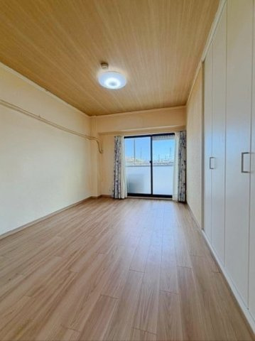 メゾン高槻古曽部の洋室|木目のフローリングが暖かみのある室内に。明るい寝室で心地のいい朝を迎えられそう。