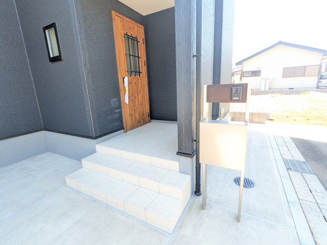 かすみがうら市下稲吉2期　新築戸建て　8号棟の玄関|お洒落な玄関ドアと洗練された外壁デザイン。家の顔にふさわしい上質な佇まいで、ご家族やお客様を迎えます。