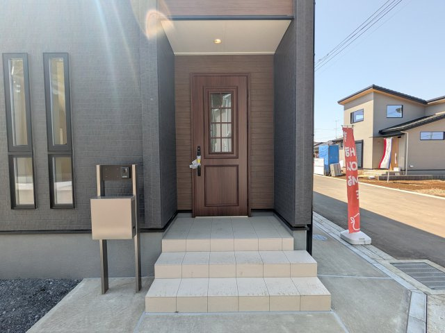 かすみがうら市下稲吉2期　新築戸建て　7号棟の玄関|お洒落な玄関ドアと洗練された外壁デザイン。家の顔にふさわしい上質な佇まいで、ご家族やお客様を迎えます。