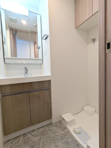 GRANSITE蔵前の洗面所|トイレと独立した洗面脱衣室、2面鏡付ハンドシャワー付洗面台、洗濯機置場は排水口のお手入れしやすい様に手前中央に配置し、足高の防水パンです