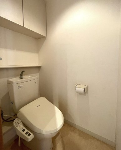 サーパス古江新町のトイレ|小物の収納に優れた吊戸棚や棚が配置されているトイレです。