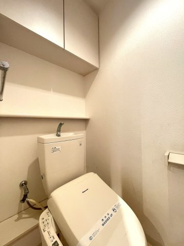 サーパス古江新町のトイレ|小物の収納に優れた吊戸棚や棚が配置されているトイレです。