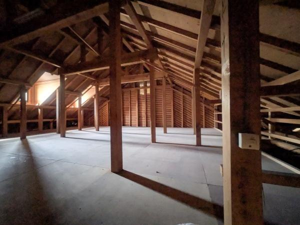 新明治5丁目　戸建のその他|屋根裏部屋の広々とした空間が印象的です。木の梁がしっかりとした構造を感じさせます。採光も確保されており明るさもあります。収納やさまざまな用途に活用できるスペースです。