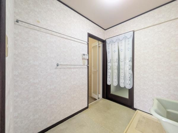 新明治5丁目　戸建のその他|落ち着いた色合いの壁紙とシンプルな内装が空間を広く感じさせる脱衣所です。明るい照明で室内がしっかり照らされています。