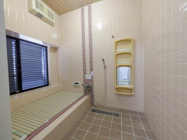 新明治5丁目　戸建の浴室|広々としたバスルームで落ち着いたタイルの色合いが特徴です。大きな窓からしっかりと換気が行えます。ミラーと収納スペースが壁面に備え付けられており使い勝手が良い空間です。
