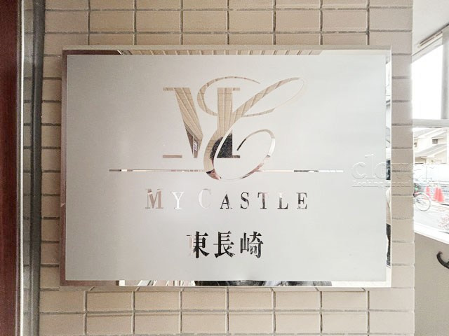 【現況写真】 | マイキャッスル東長崎 | エントランスに掲げられた、マンション名を示す館銘板。さほど激しく主張はしませんが、しっかりと掲示されています。～即日のご見学可能～　お問合せはお気軽にどうぞ。